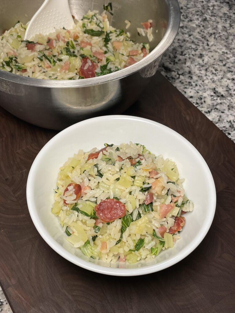 A bowl of rice with Chinese sausage, ham, and bok choy