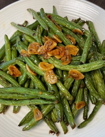 Plate of green beans garnished with sliced garlic