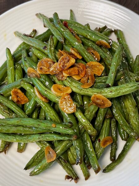 Plate of green beans garnished with sliced garlic