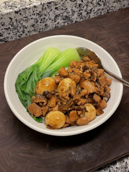 Bowl of rice topped with saucy diced chicken and quail eggs, with blanched bok choy on the side