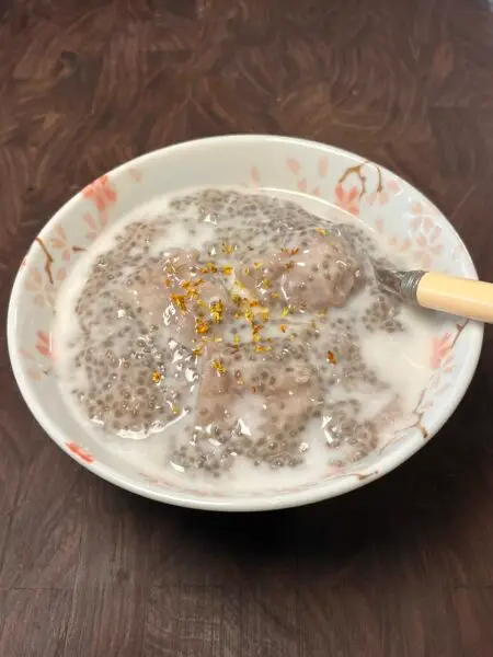 Bowl of chia pudding with taro chunks, topped with coconut milk and dried osmanthus