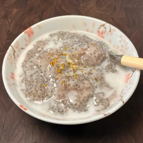 Bowl of chia pudding with taro chunks, topped with coconut milk and dried osmanthus