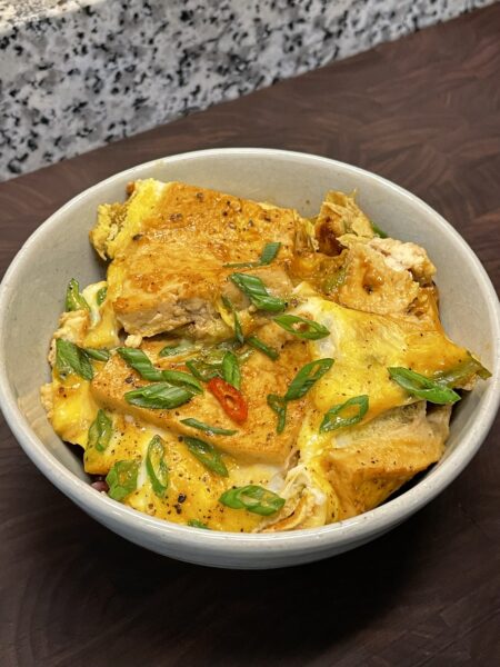 Bowl with a tofu and egg dish, garnished with sliced Thai red chili and scallions