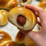 Chinese bakery-style hot dog bun, held above a tray of breads