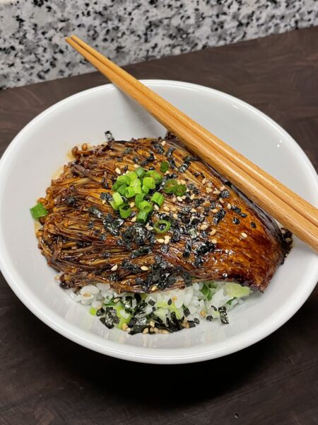 Soy glazed enoki mushroom "steaks," garnished with furikake (Japanese seaweed and sesame seasoning) and chopped green onions, served over a bed of white rice mixed with chopped vegetables