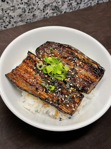 Soy glazed zucchini, garnished with furikake (Japanese seaweed and sesame seasoning) and chopped green onions, served over a bed of white rice